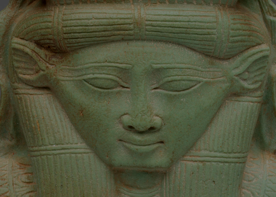 Detail of the jade sculpture’s base, which forms a head with triangular ears, almond shaped eyes, and long eyebrows. Its headdress and hair are textured with rows of etchings.