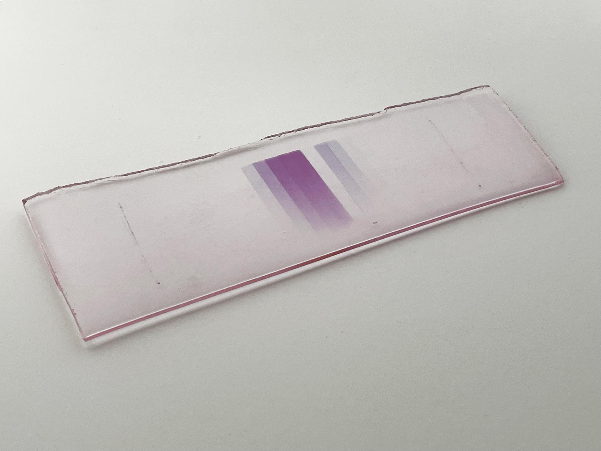 A piece of glass with a gradient of purple lines at its center.