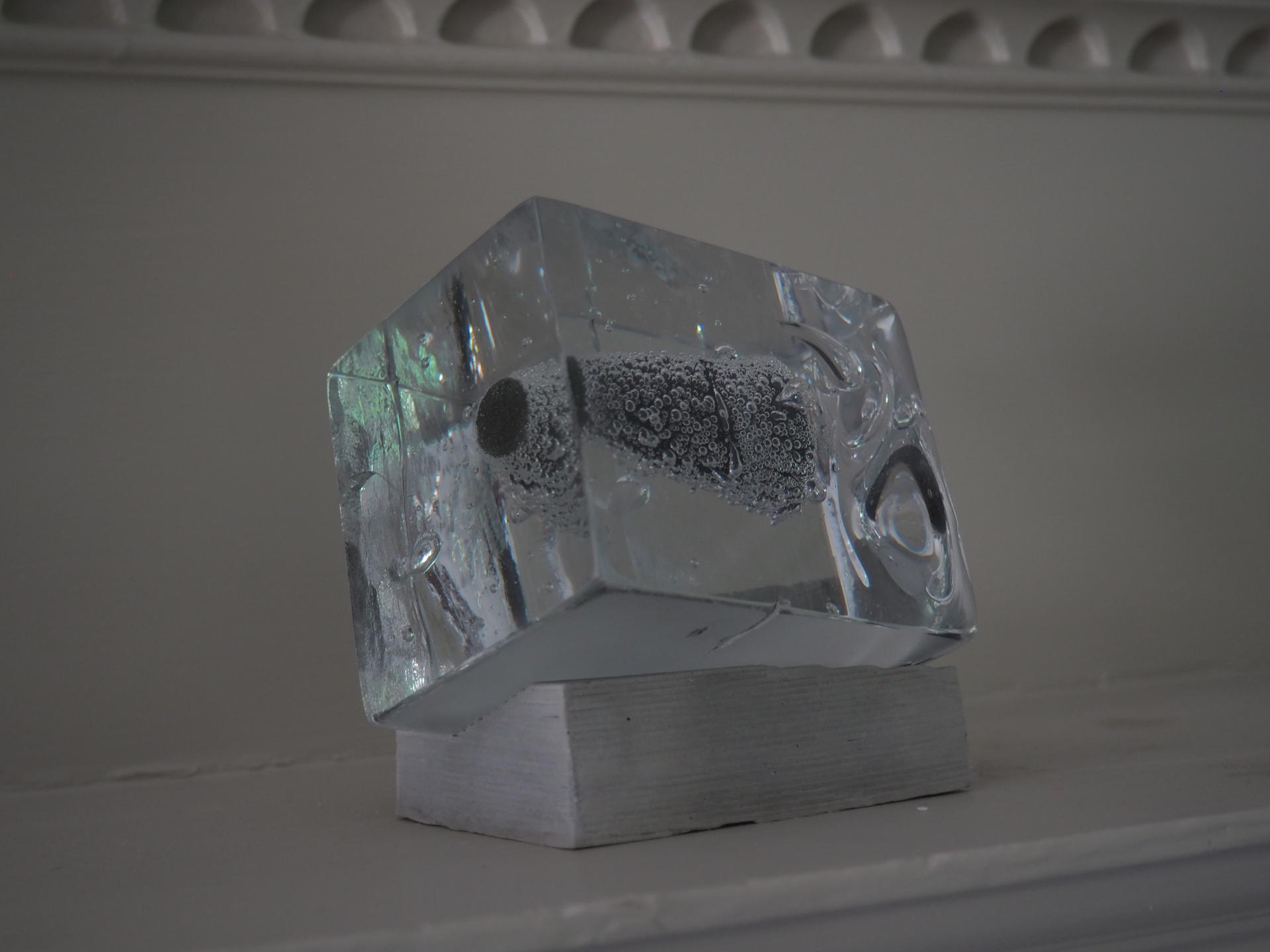 Bubble covered cone encased in glass on a fireplace mantle.