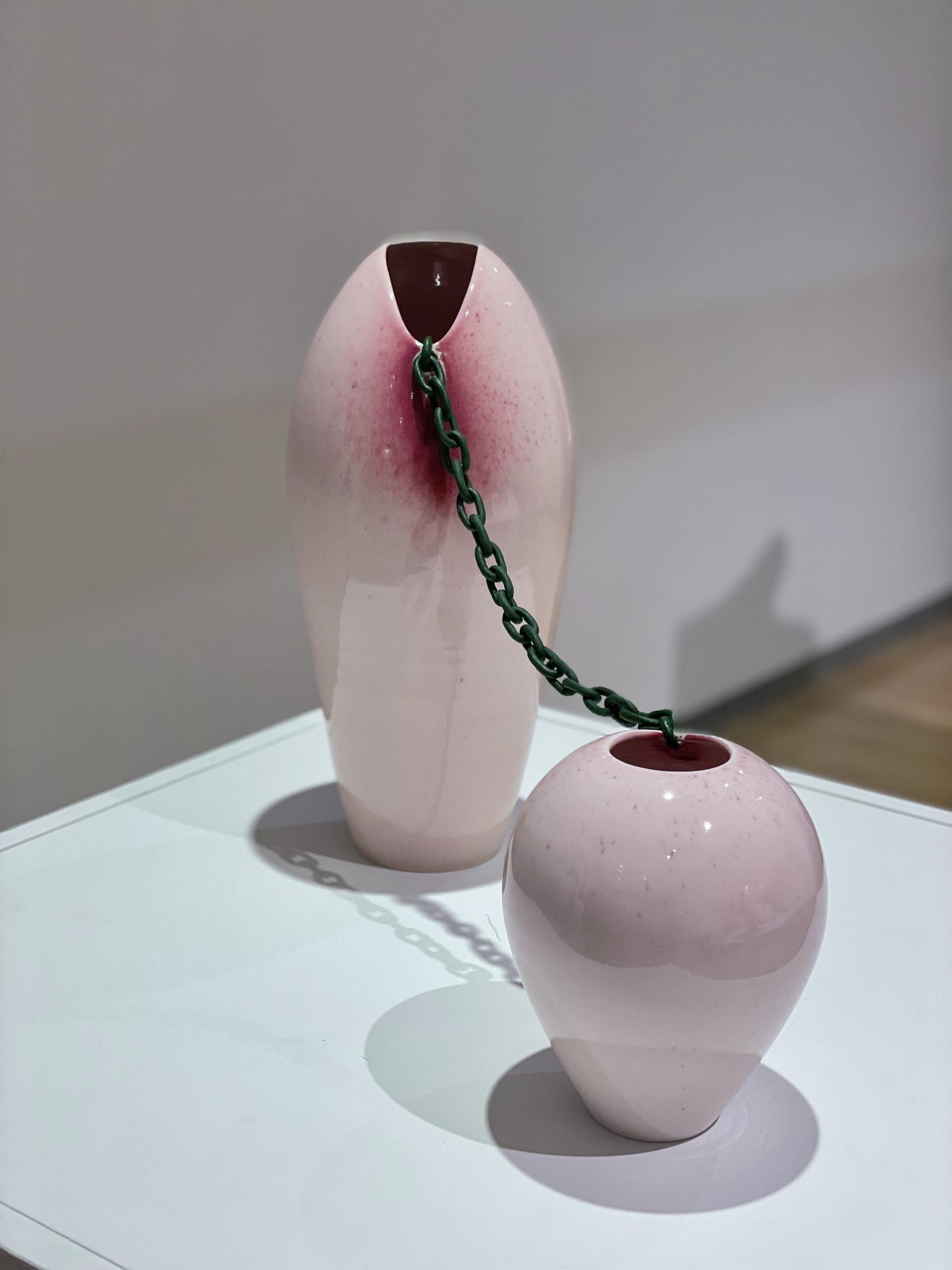 Two vases are connected by a hand-sculpted ceramic chain. 