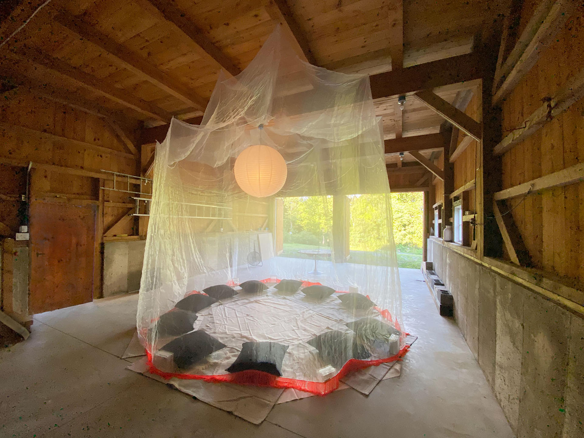 The interior of a barn with a large circular mosquito net hanging from the ceiling