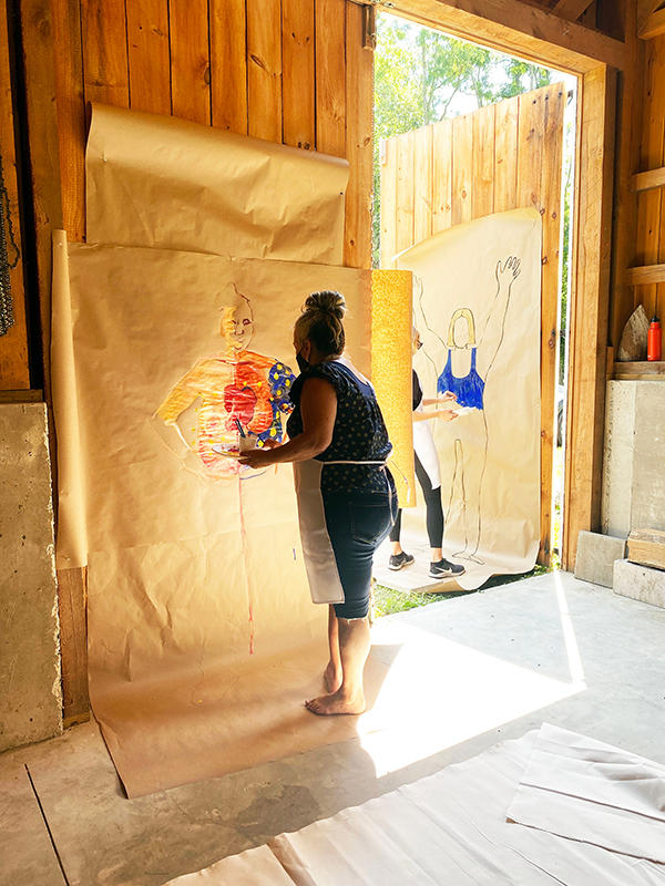 A woman painting a life-sized self portrait.