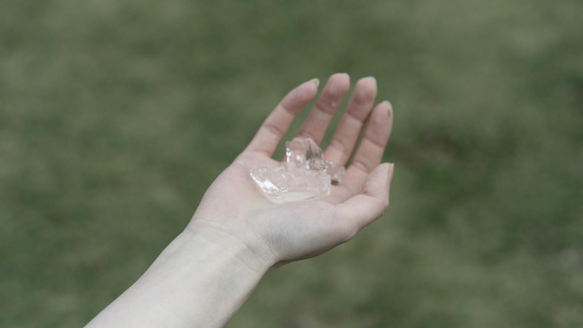 One hand holding a fragment of an ice lens.