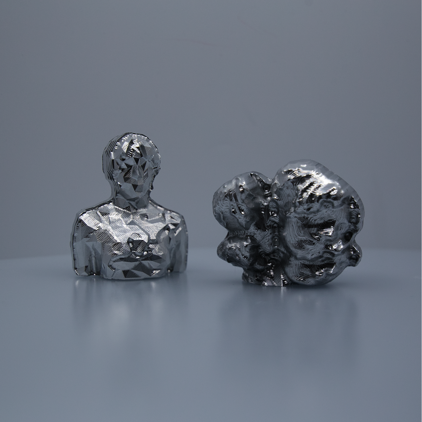 Two small metal sculptures sit next to each other.