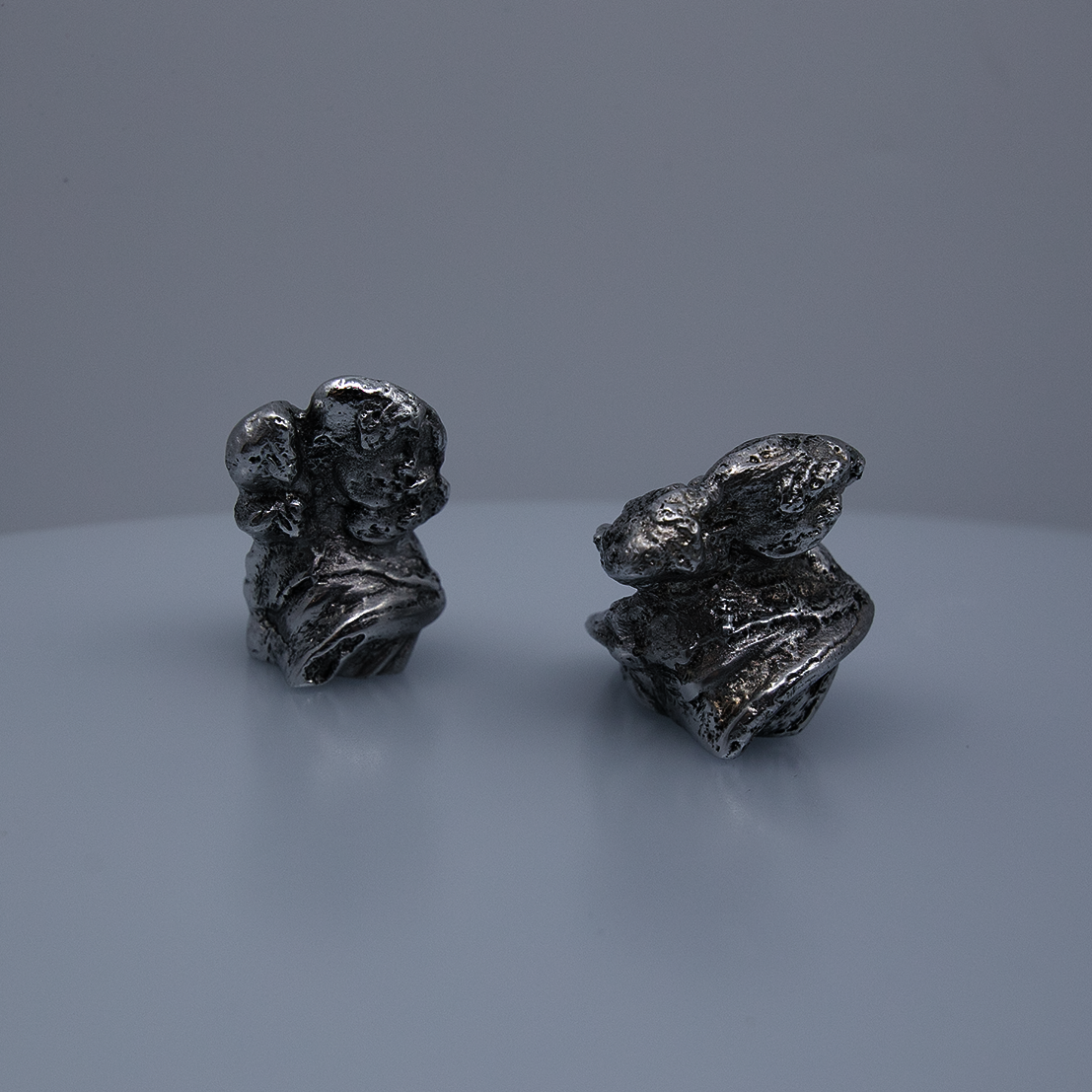 Two small aluminum figures with multiple heads.