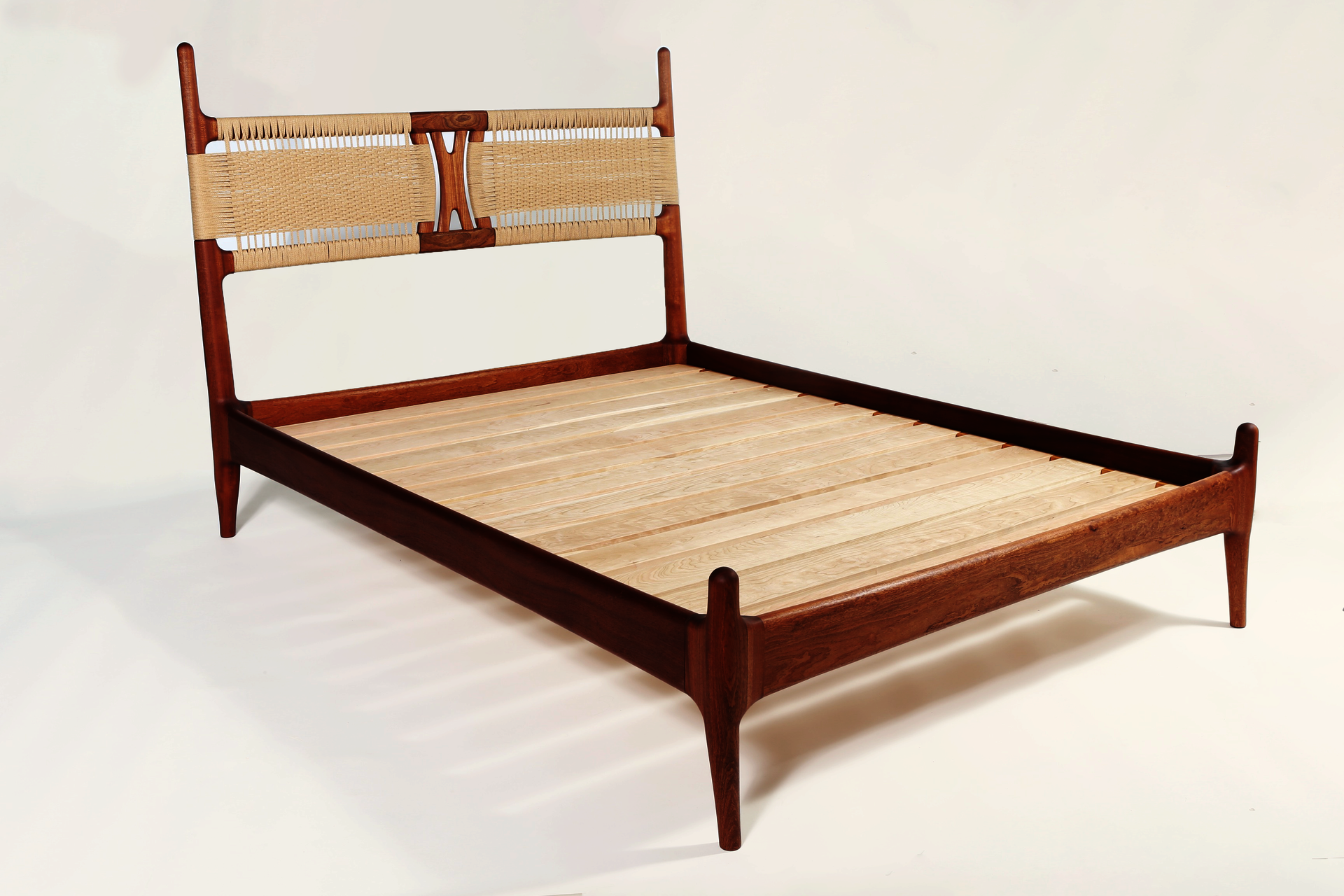 Sapele wood bed frame with woven papercord headboard on white background