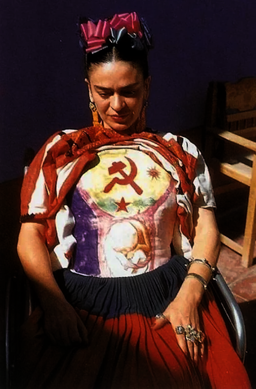 Photograph of Frida Kahlo seated in a wheelchair wearing a cast that has a hammer and sickle painted on it