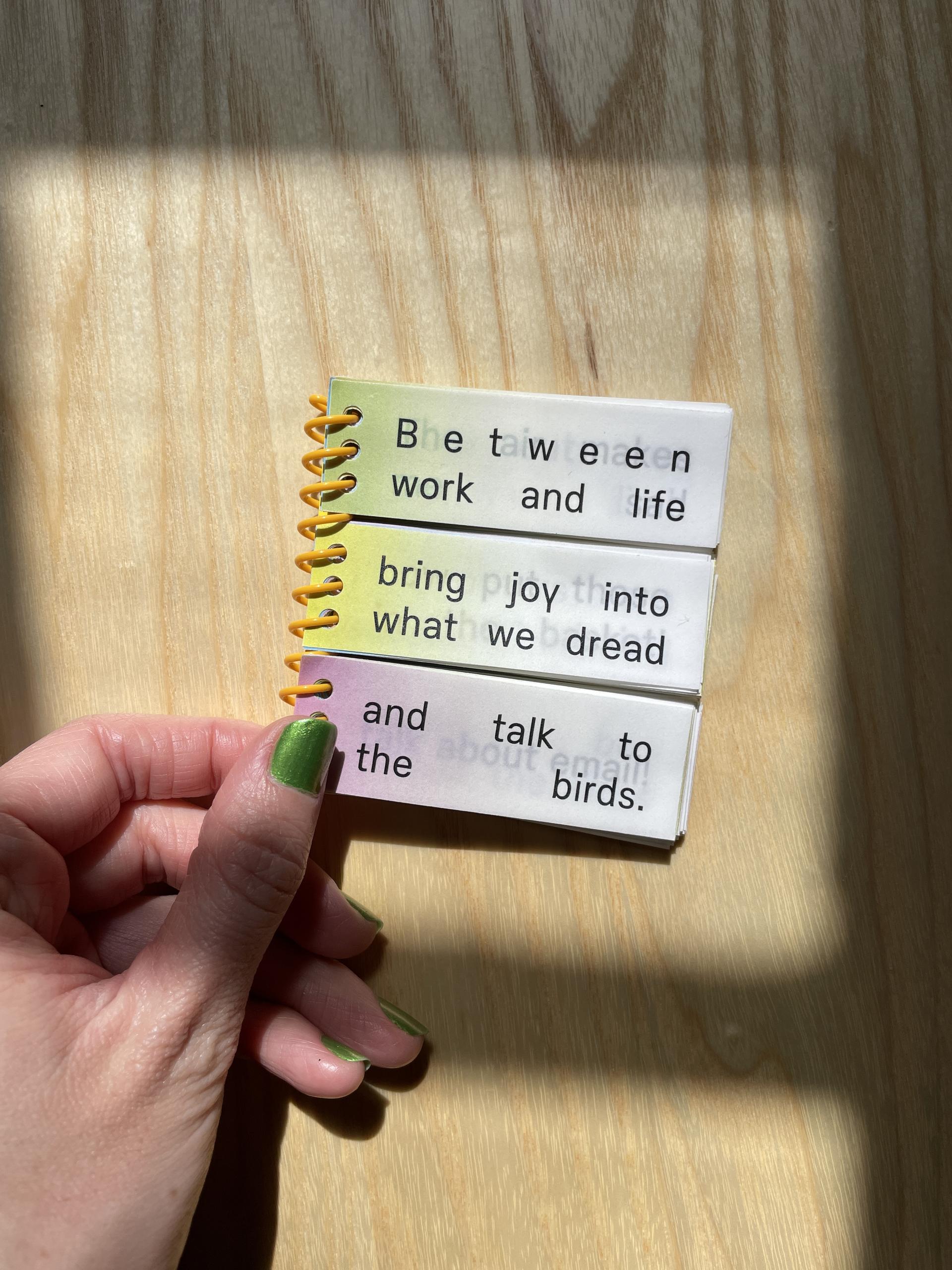 A spiral-bound book with three physically separated sections that together read “Between work and life, bring joy into what we dread, and talk to the birds.”