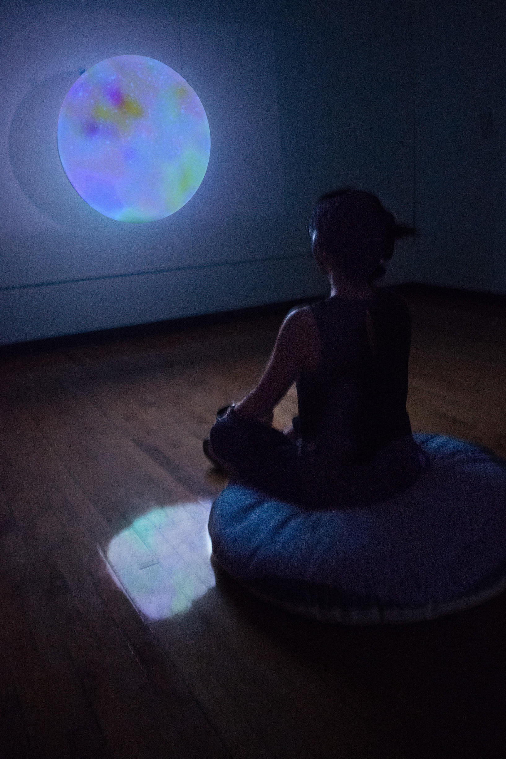 Projected glowing image with person sitting cross-legged in front of screen
