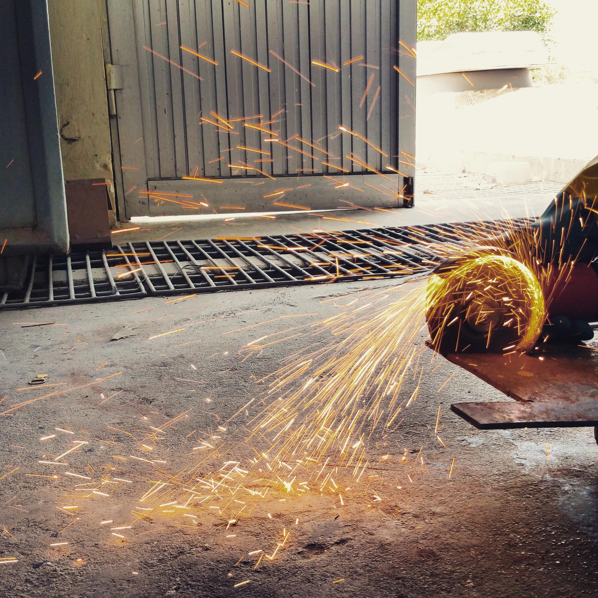 A metal sheet being cut by an angle grinder portraying the element of learning by doing.