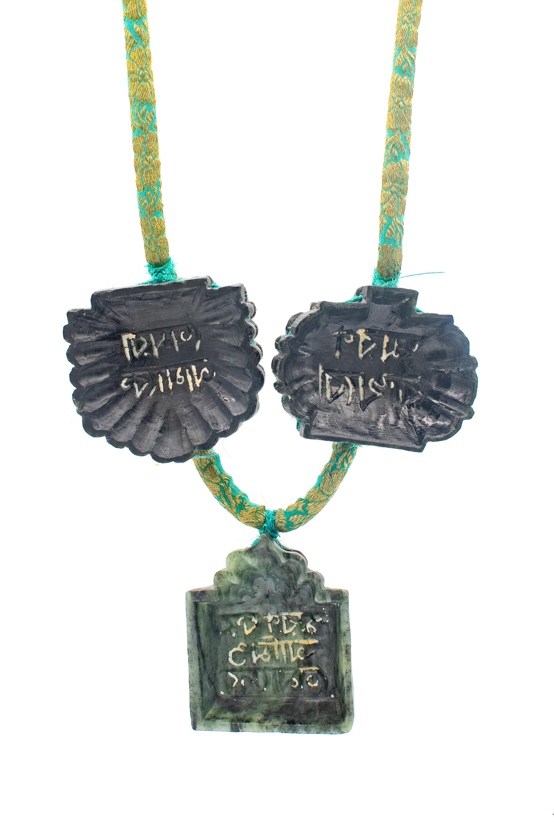 Detail of necklace with five soapstone molds carved with bangla script with shondesh residue.