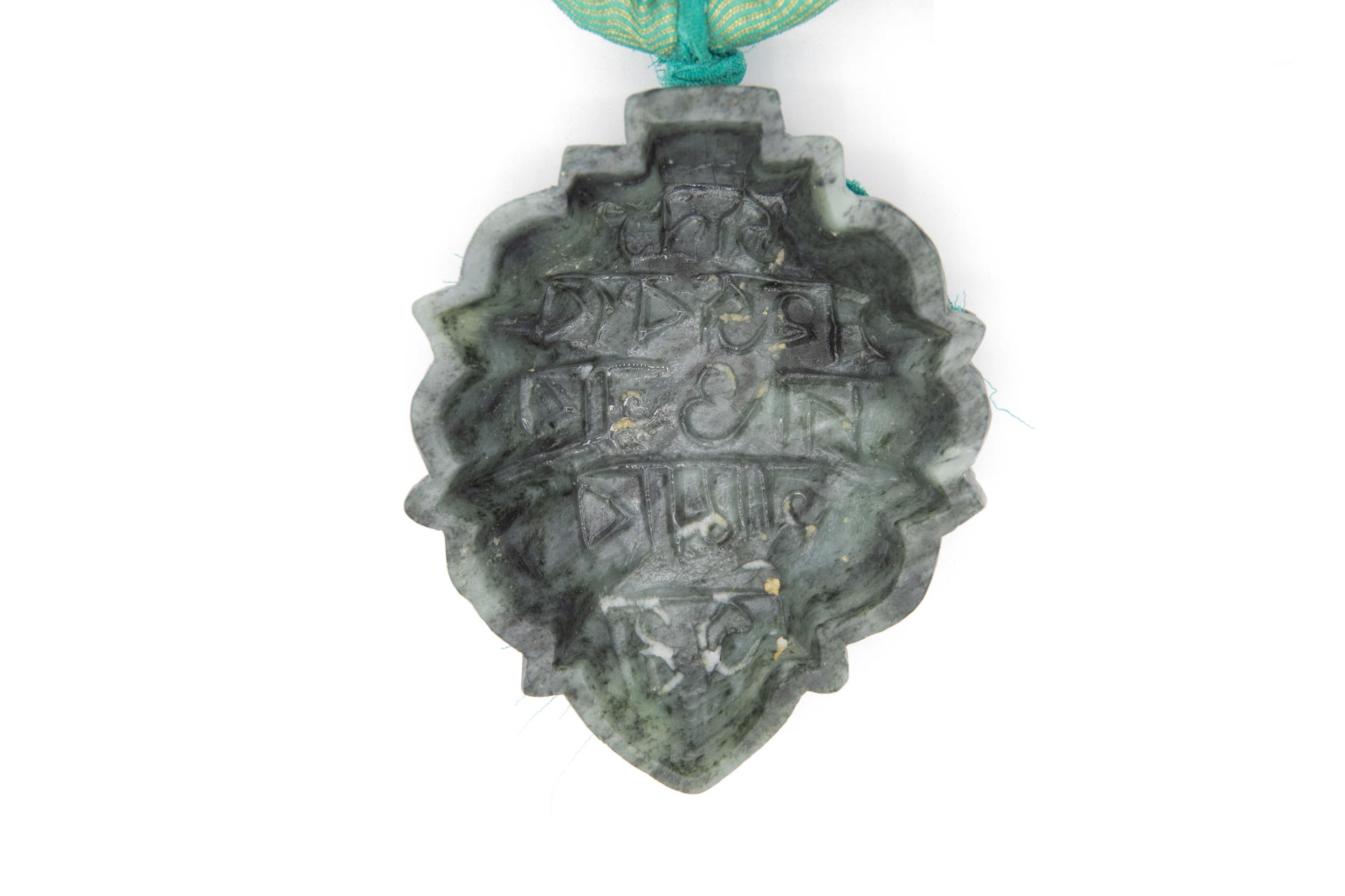Detail of necklace with three soapstone molds carved with bangla script with shondesh residue.