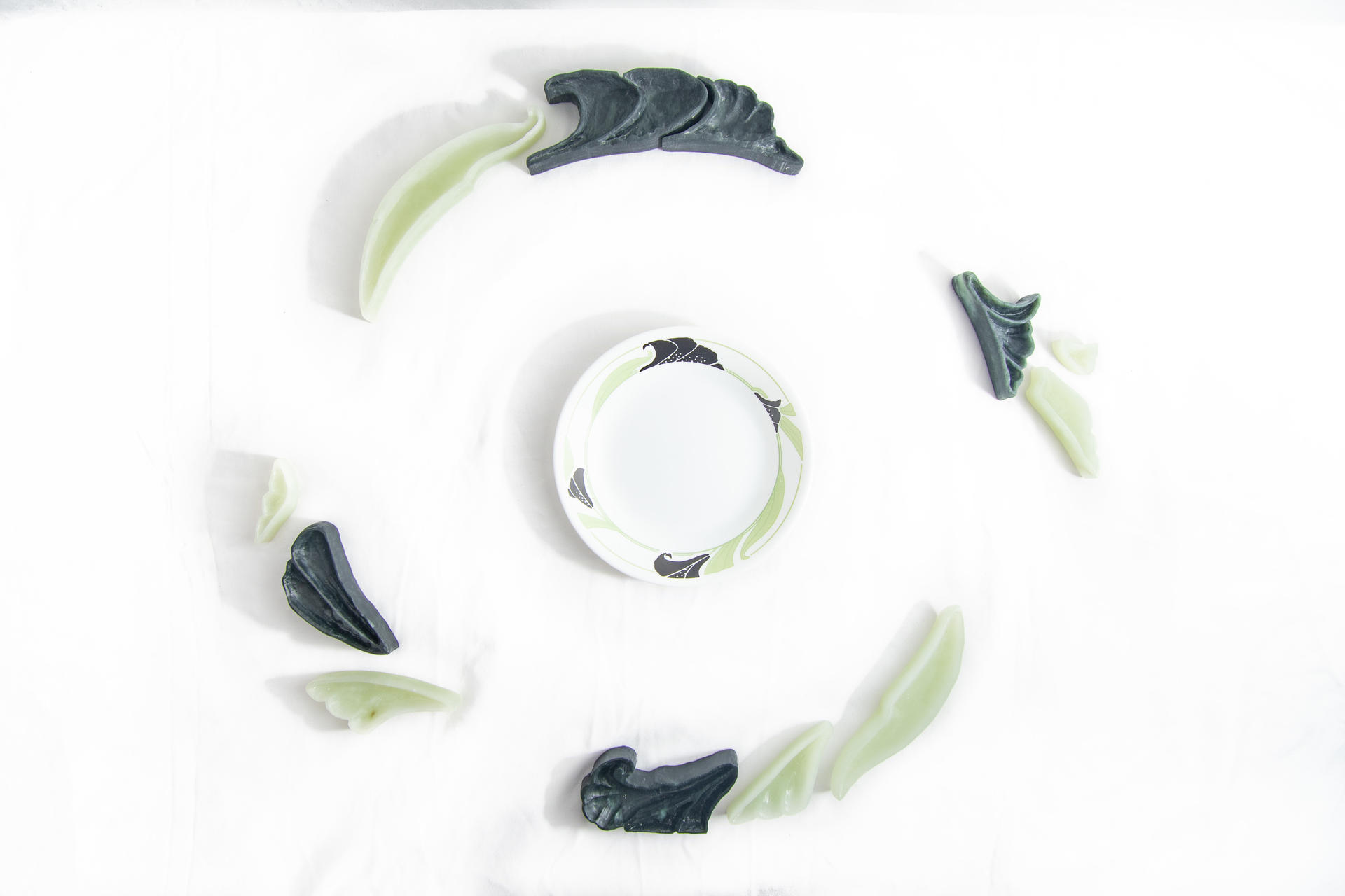 Carved soapstone arranged in a circular pattern around a small plate with the same black and green pattern