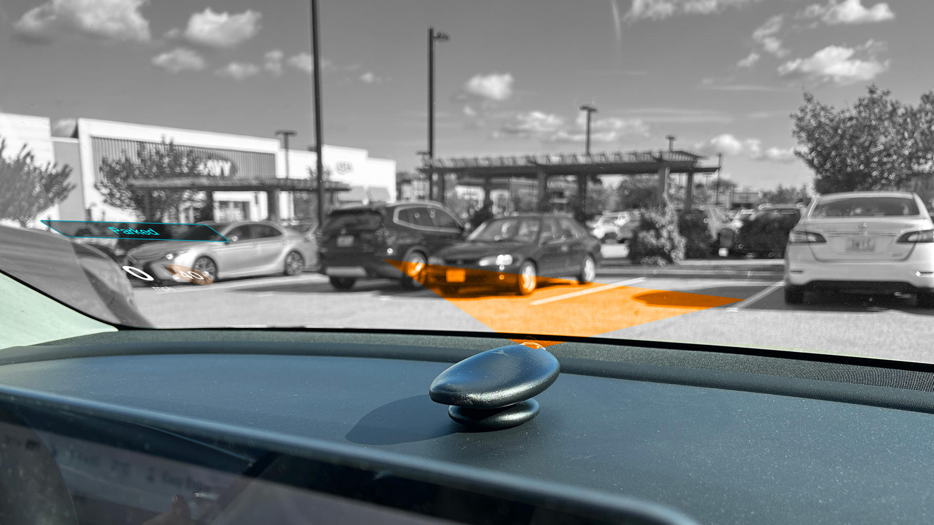 The Orca placed on the dash of a car projecting onto the windshield. The orange represents the projection angle. In the bottom left corner parts of the overall UI can be seen.