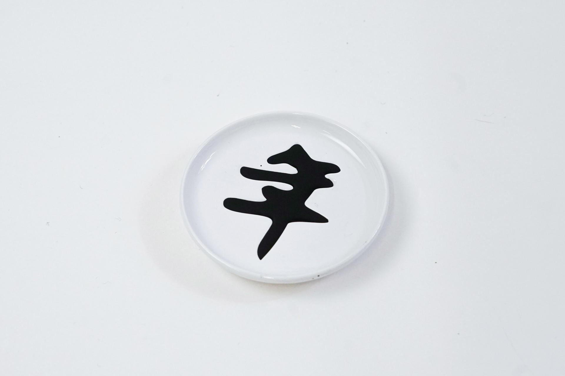 A white dip sauce dish with a black Chinese character in it