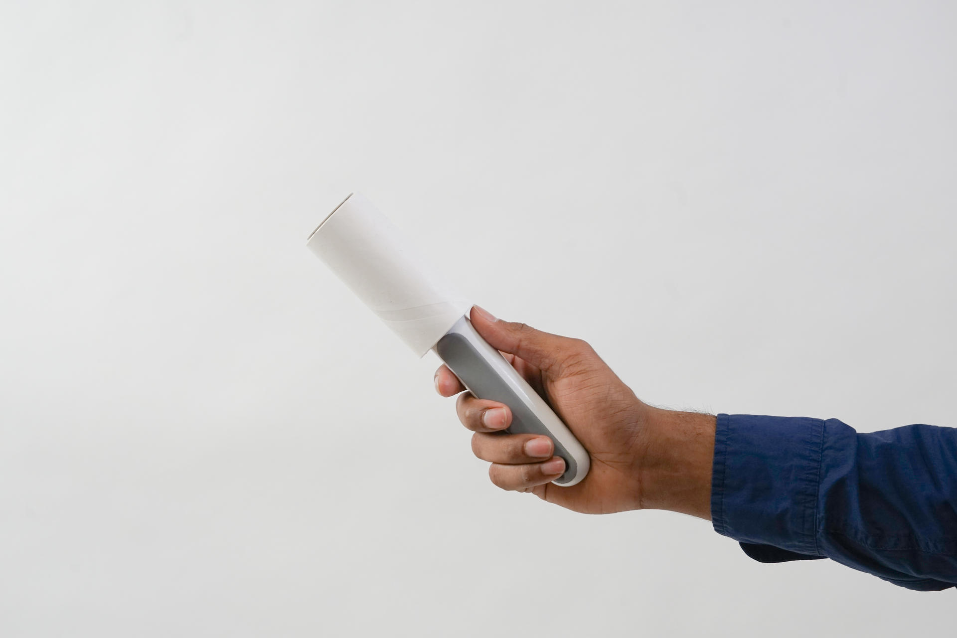 A hand holding a white and grey lint roller