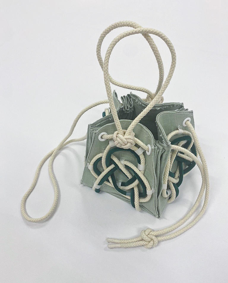 A green cube bag wrapped with cords on a white background