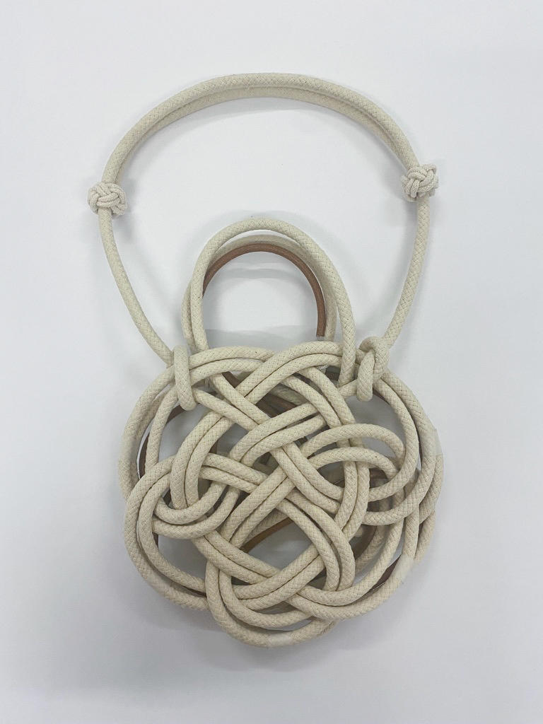 An ivory bag made with cords on a white background