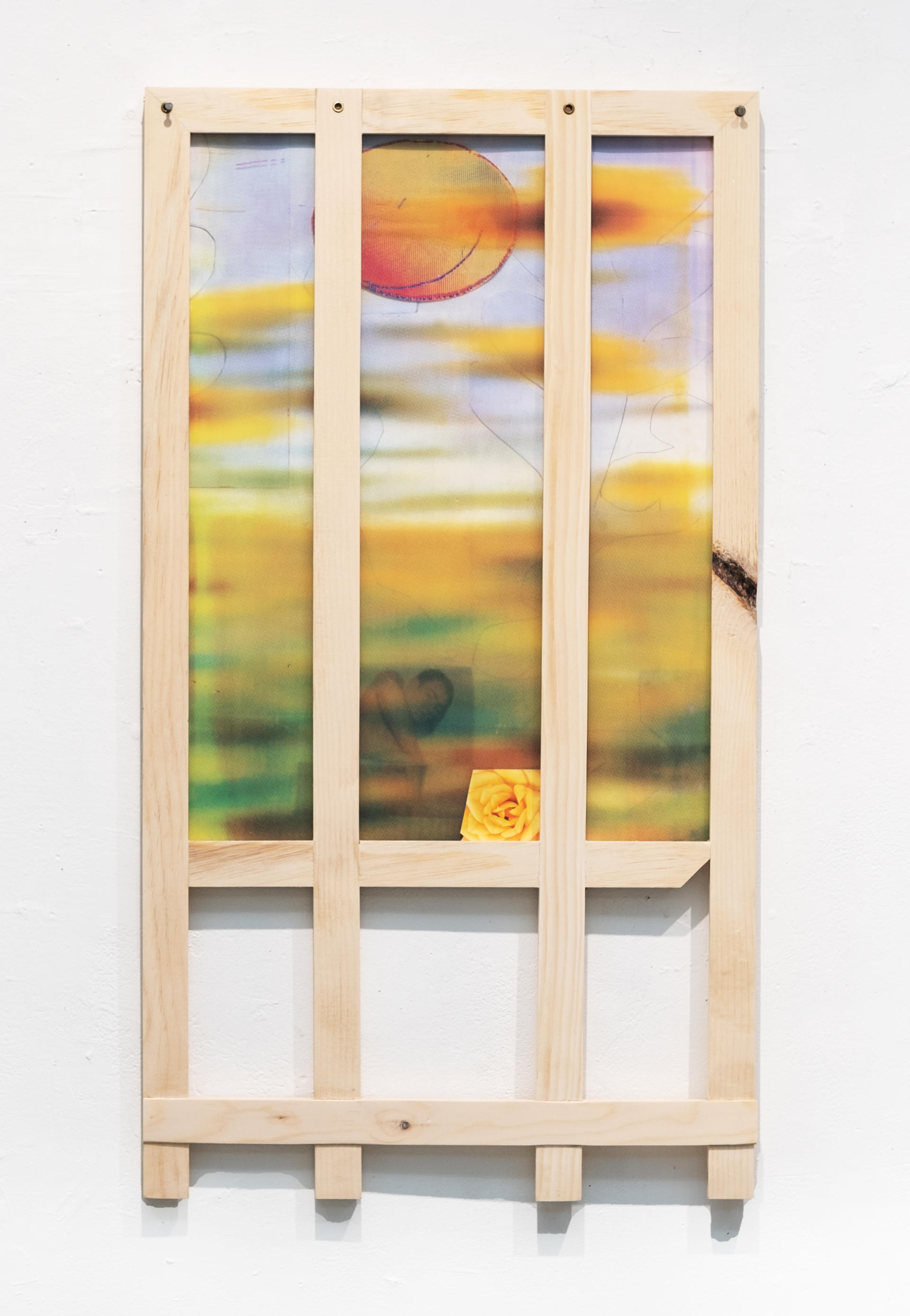 a picket fence-like frame houses a blurry screenprint of yellow flowers 