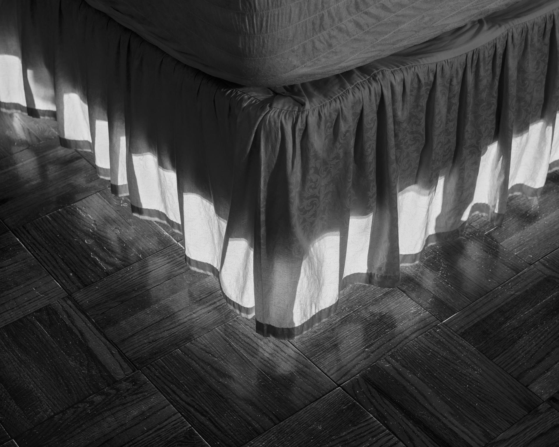 Black and white pigment print of bed skirt illuminated from behind. 