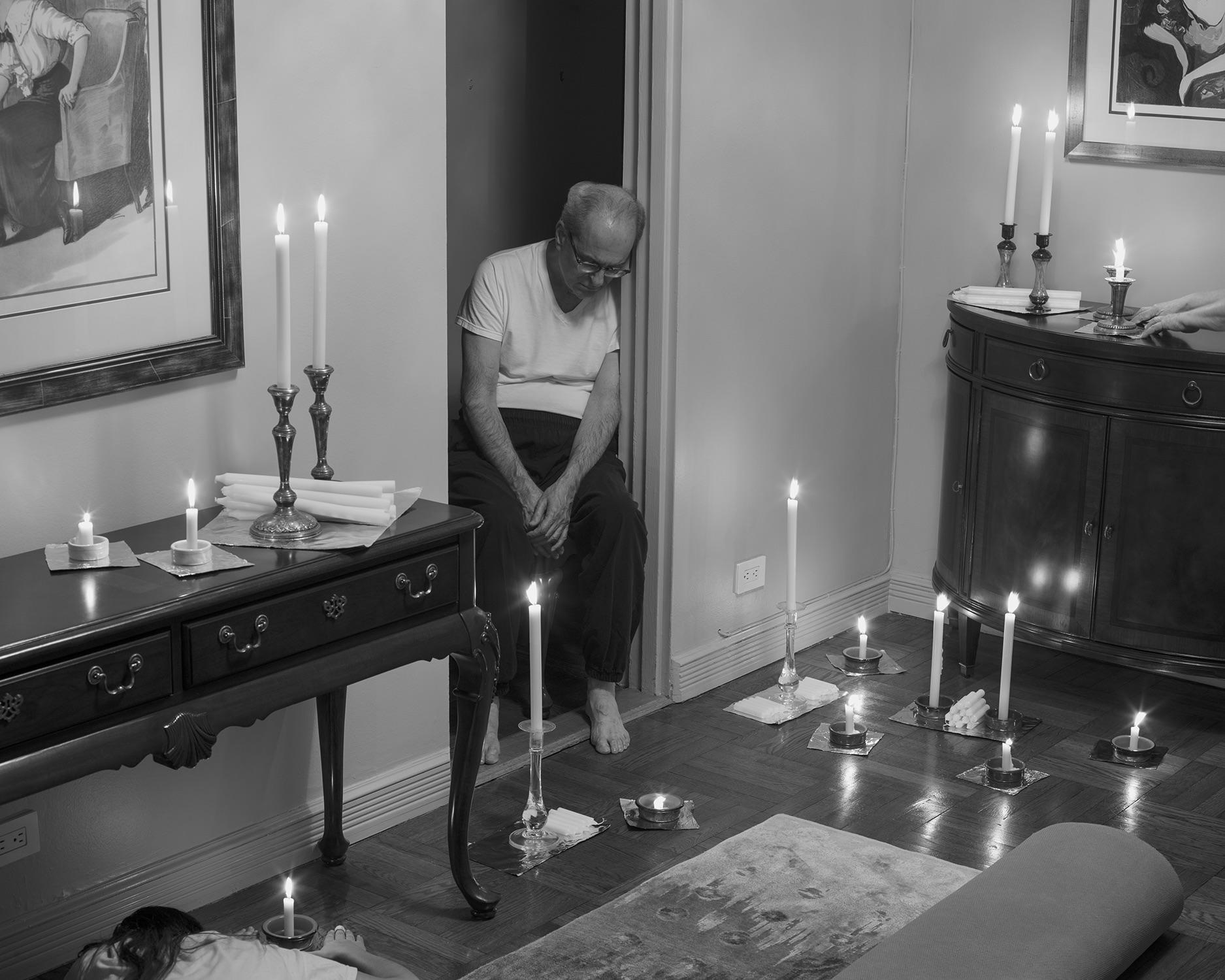 Black and white pigment print of living room with sprawling candle arrangement.