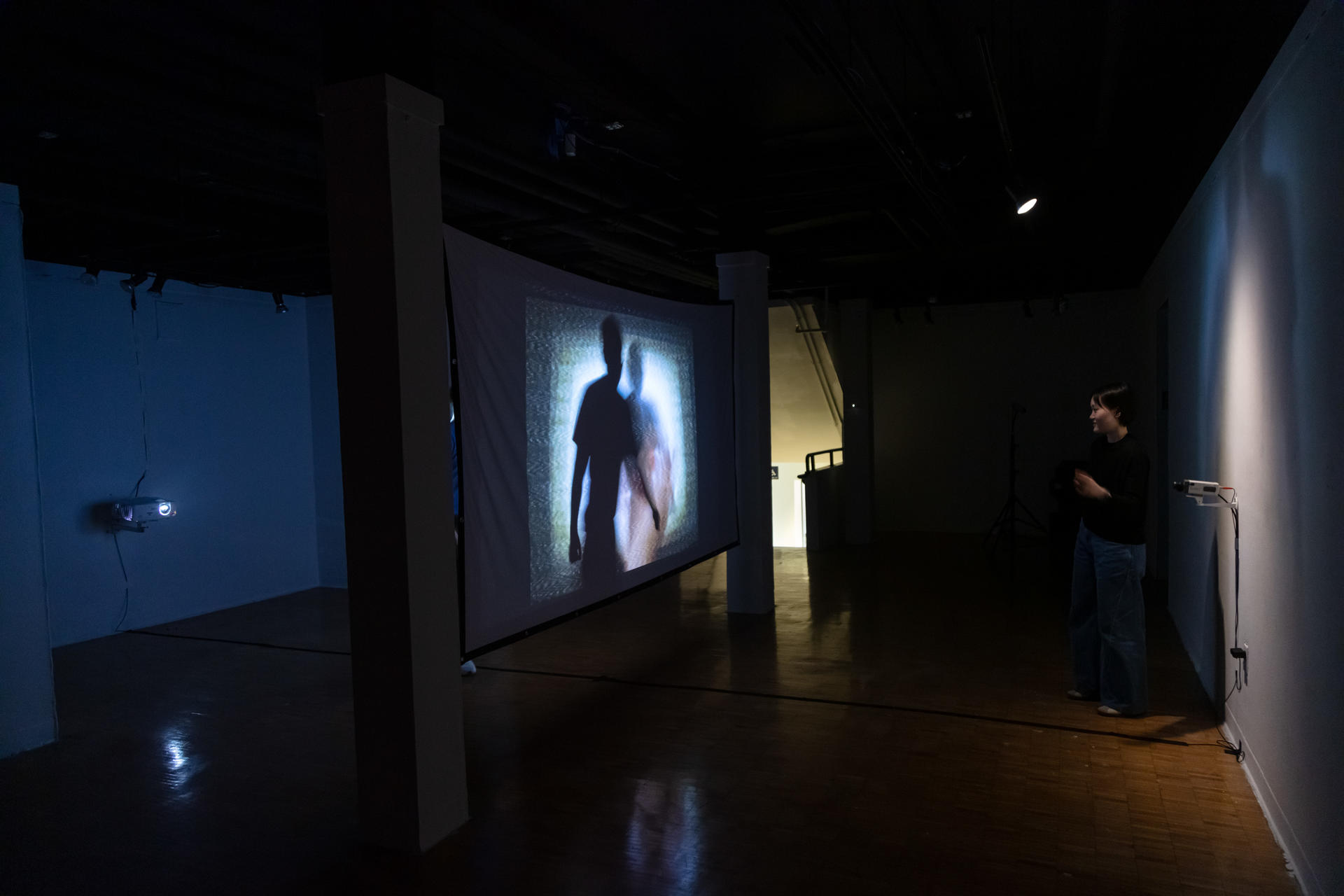 Person in front of projection screen with their image projected onto the screen