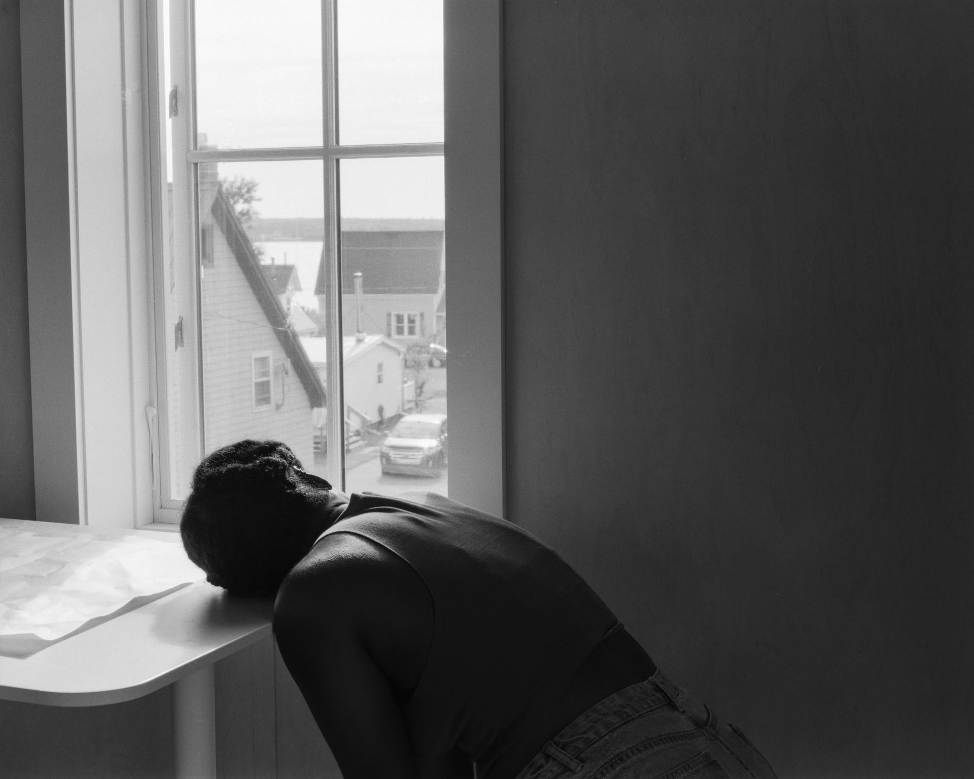 a table is in front a window and a person leans their head over 