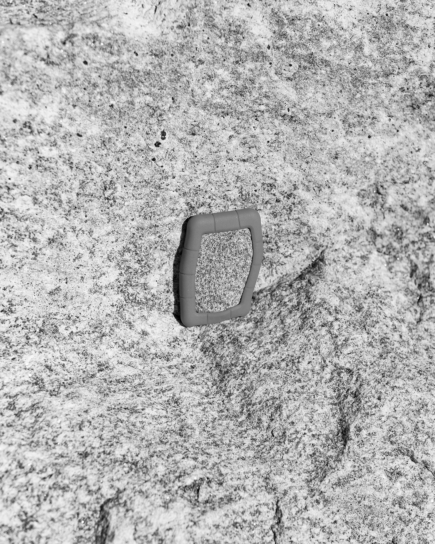 A black and white photo of a granite rock encased in a silicon hard drive cover, positioned against a similar looking granite rock.