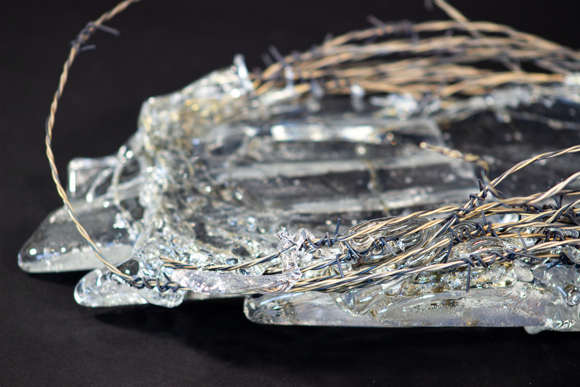 Roll of hand-woven barbed wire with molten glass encasing some parts of it.