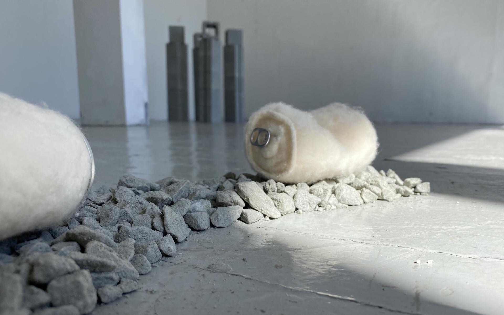 A felted aluminum can sits atop a bed of loose gravel.  