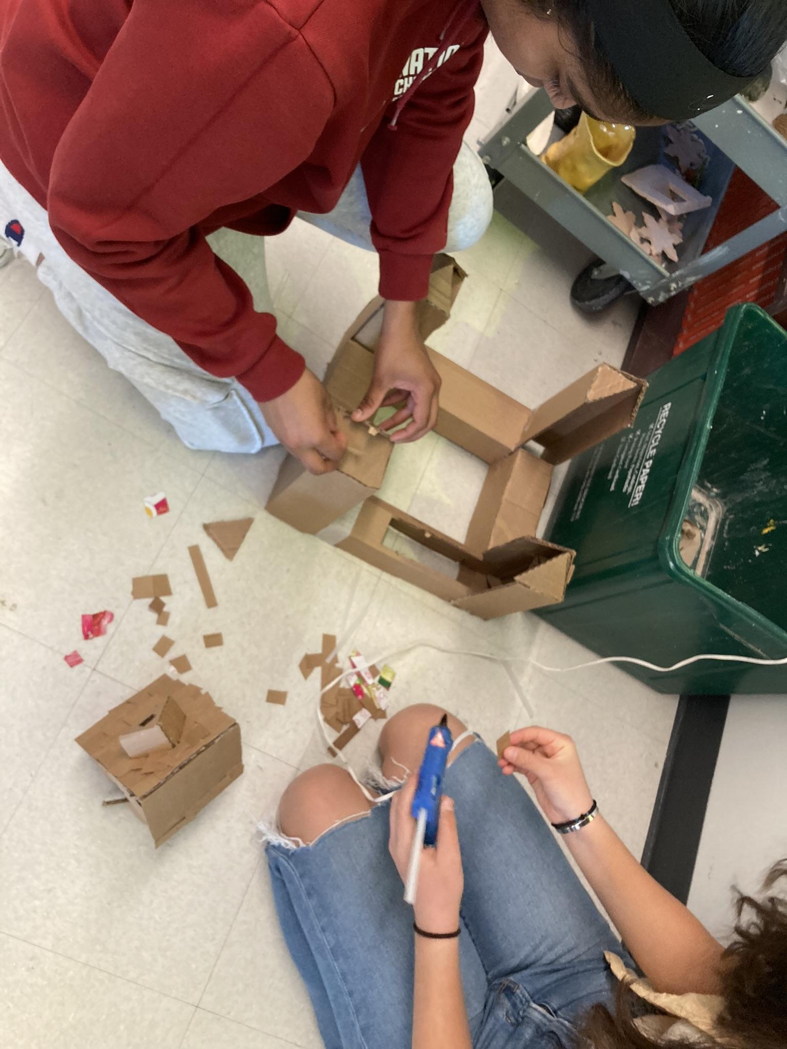 High school students build sculpture with cardboard and hot glue