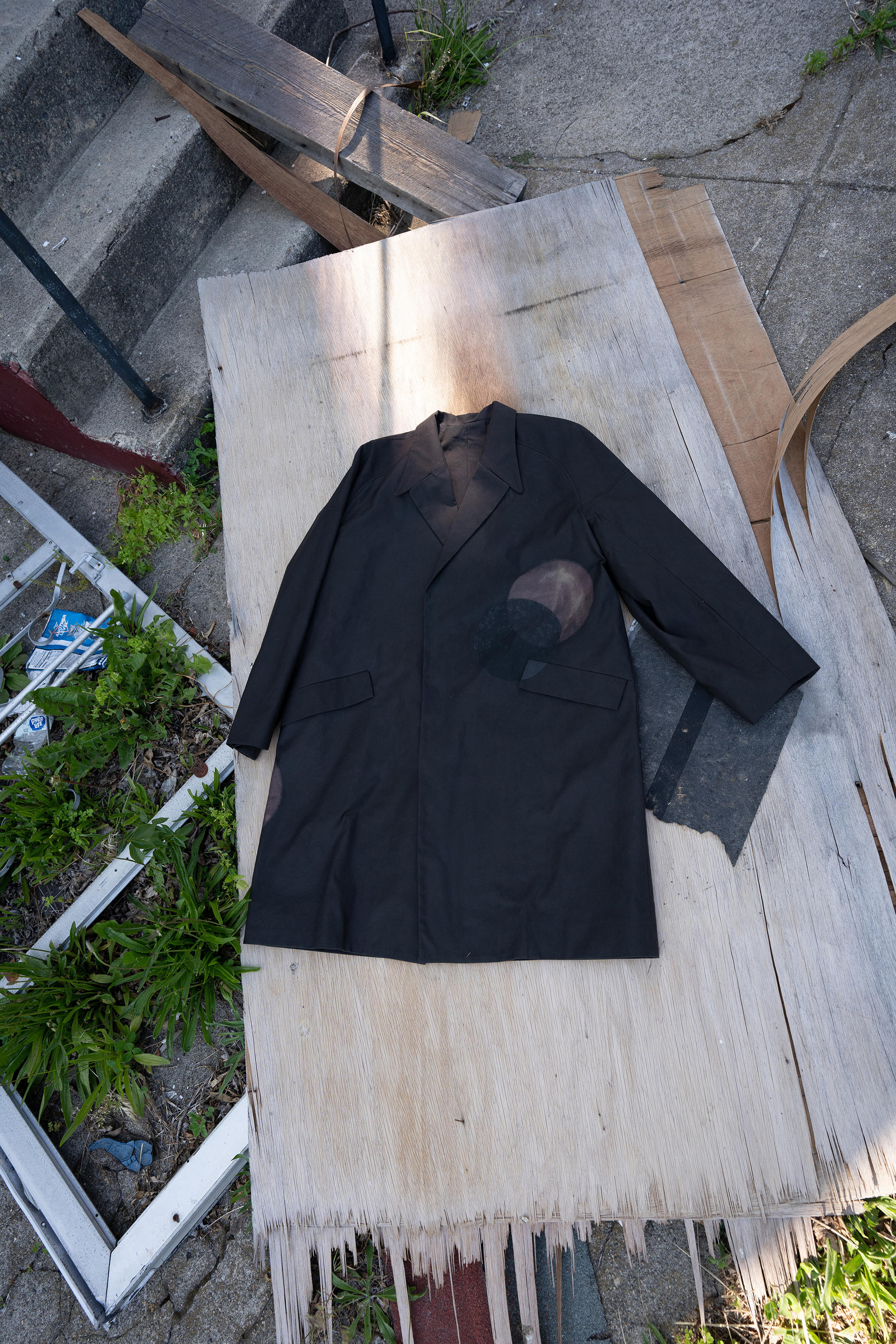 black coat on a piece of discarded wood on the ground