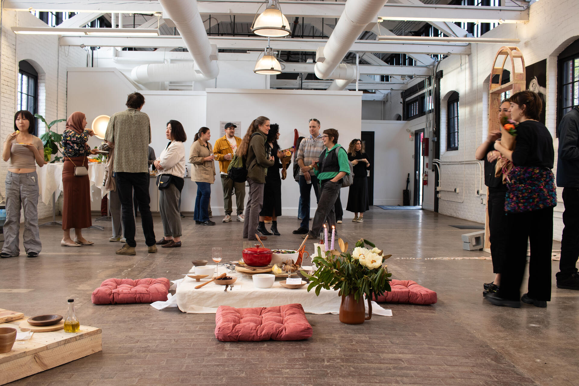 A low dining set up for four people in the middle of a gallery opening surrounded by people.