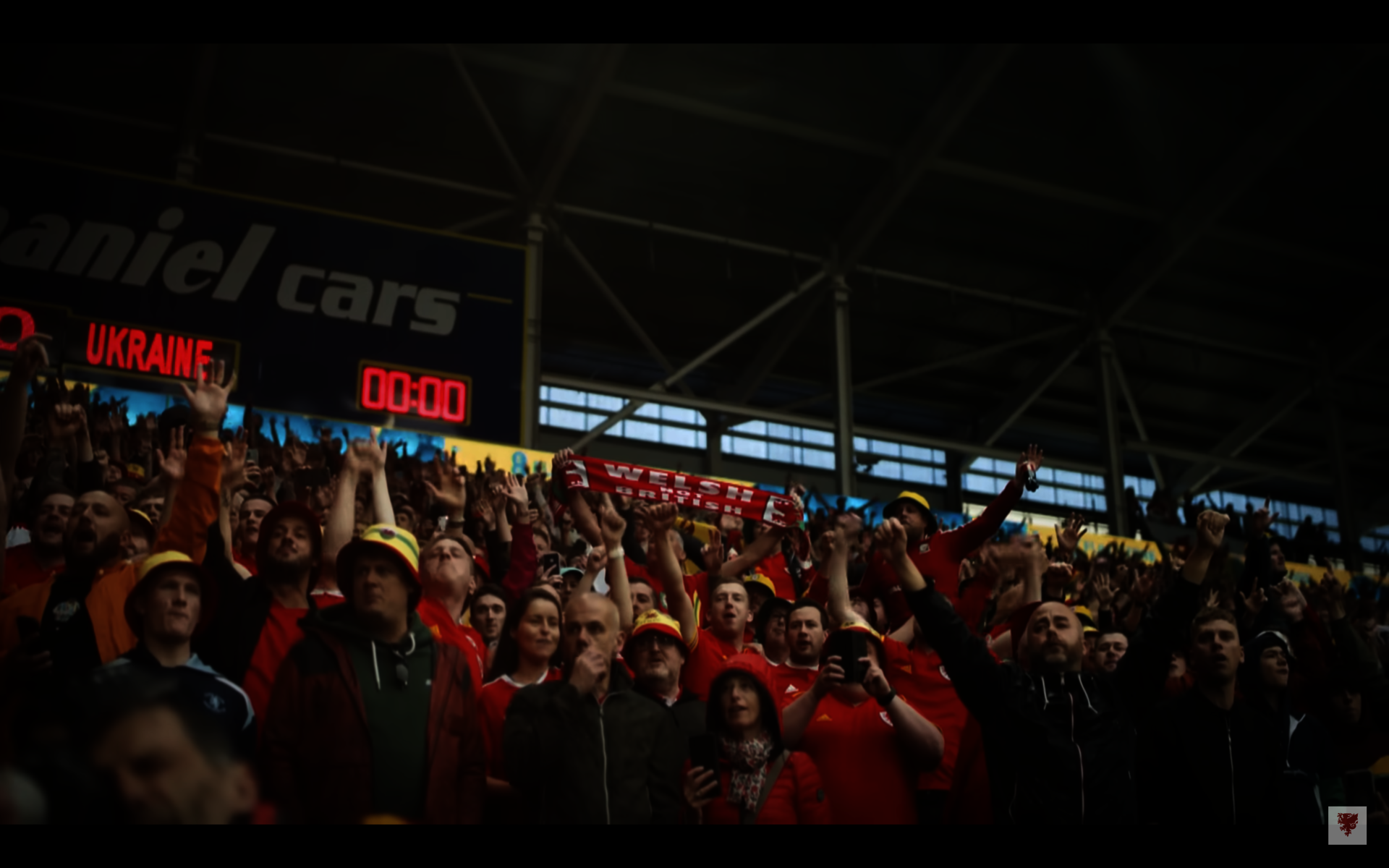 A Welsh football fan in a crowd holding a scarf with the words "WELSH NOT BRITISH."