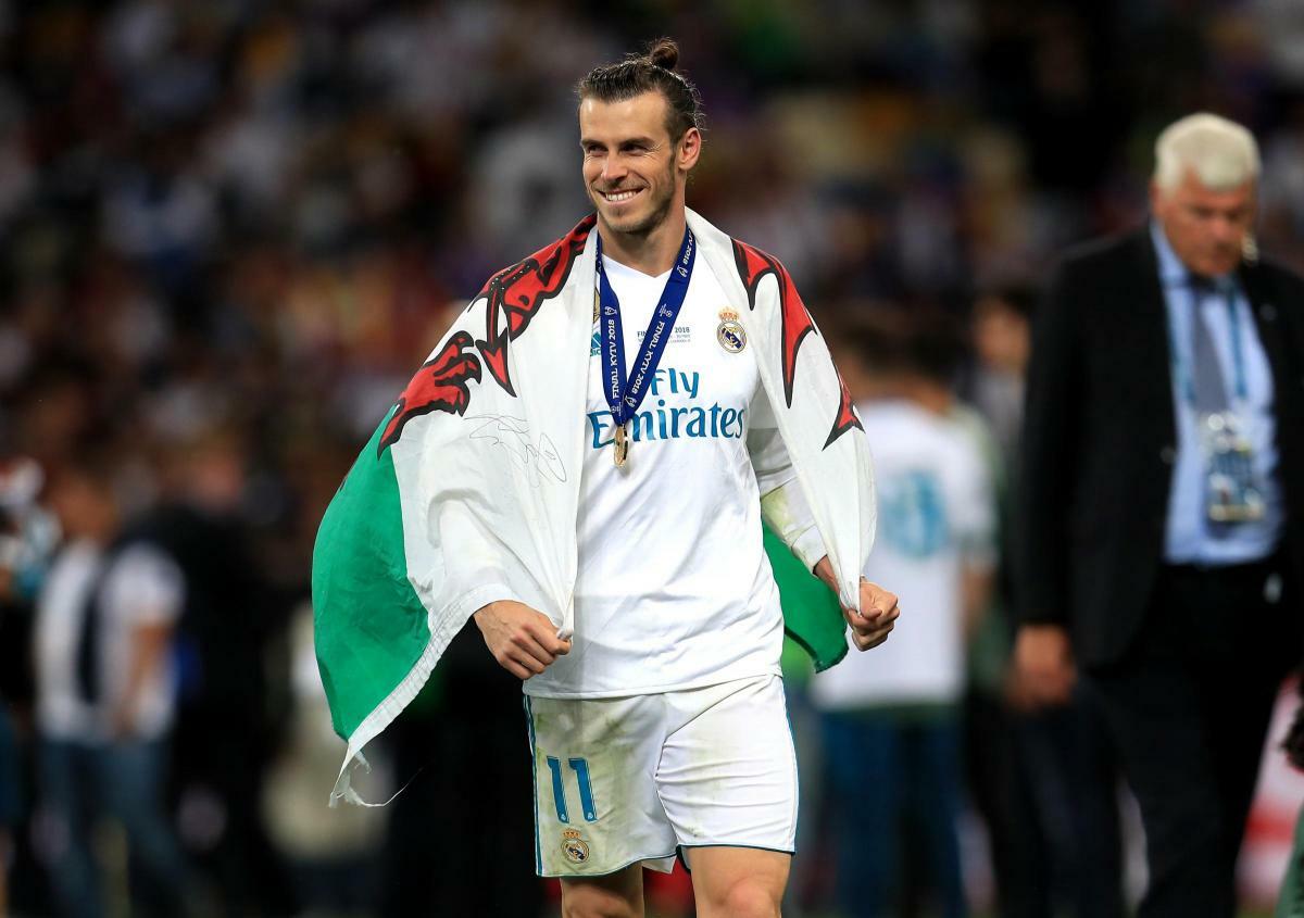 Welsh footballer Gareth Bale holding a Welsh flag while celebrating with football club Real Madrid.
