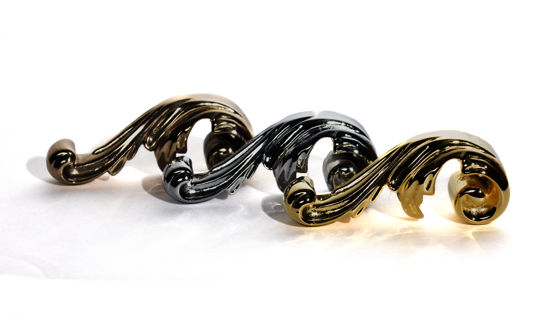solid cast bronze acanthus leaf ornaments. Three are viewed from the side in line with eachother, one is polished bronze, one is gold-plated, one is chrome-plated