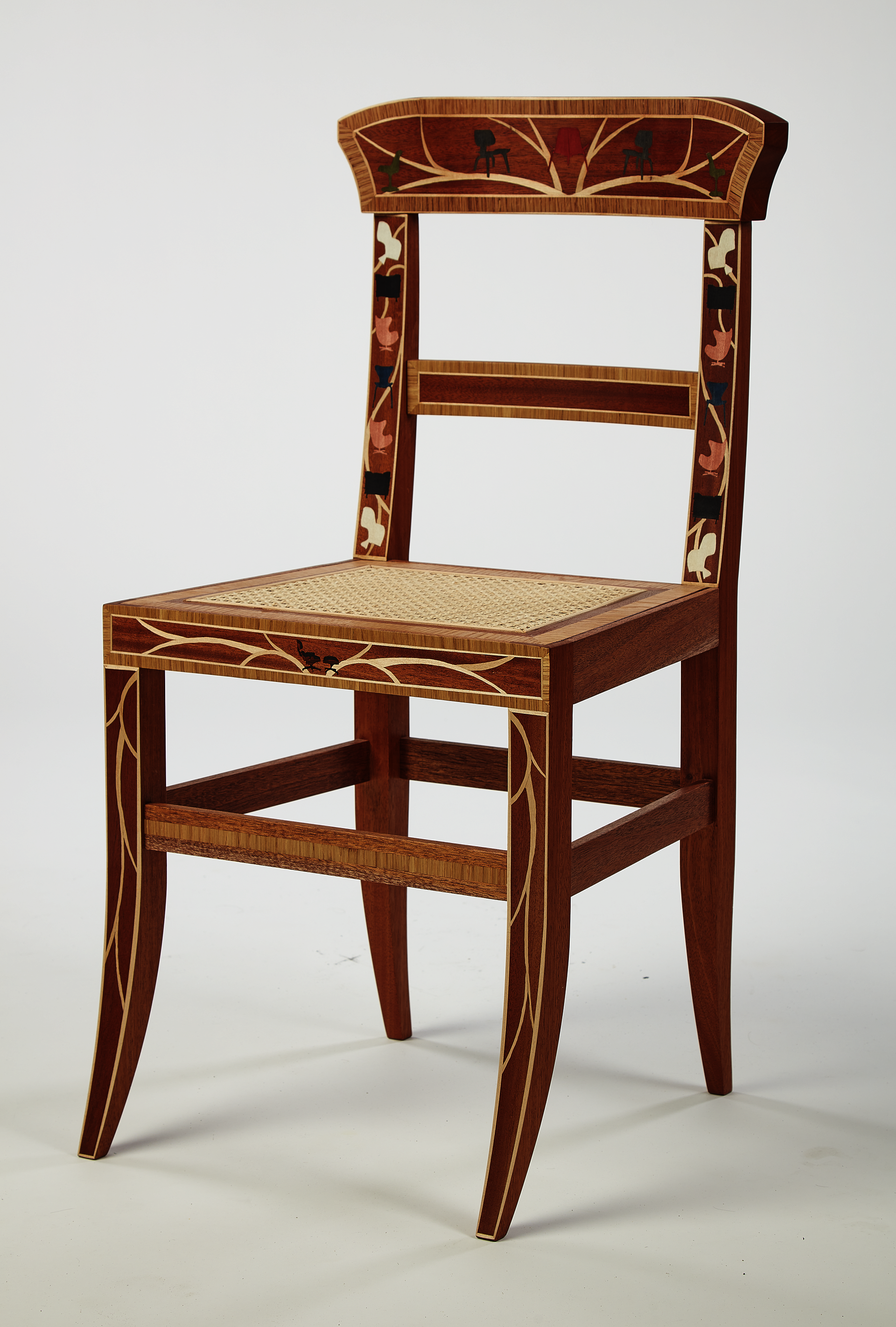 Mahogany chair in an antique style viewed from three-quarter orientation. Colorful inlays in the shape of modern chairs cover and decorate the surface.