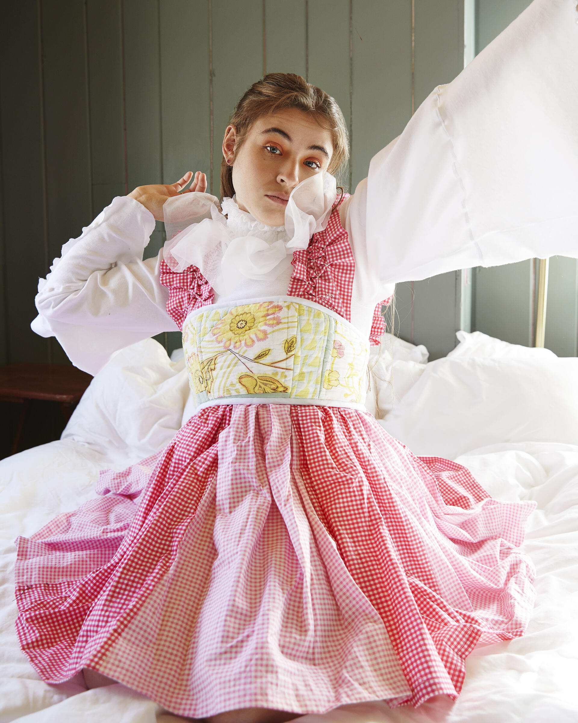 Girl stretching in pink gingham dress with floral green and yellow corset