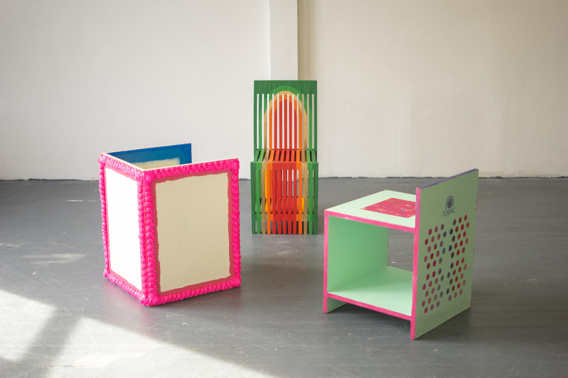 Three colorful ornamented chairs sit in the middle of a room.