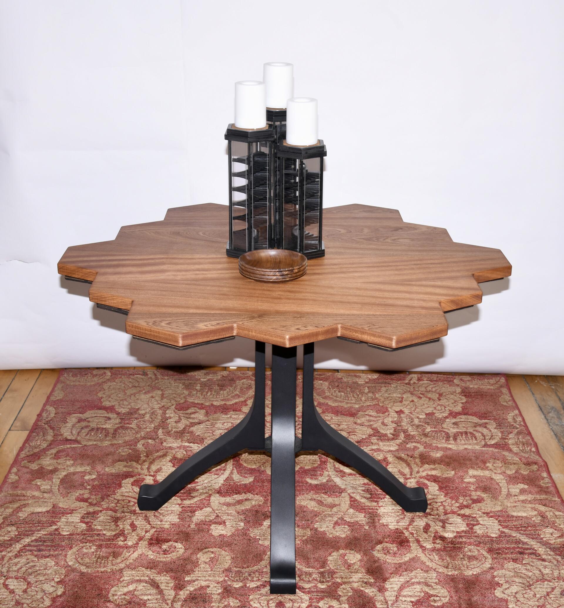 Wood table with three hexagonal candle sticks on top. A bowl on the hexagonal table. Woodeb table top metal legs. Honeycomb table shape.