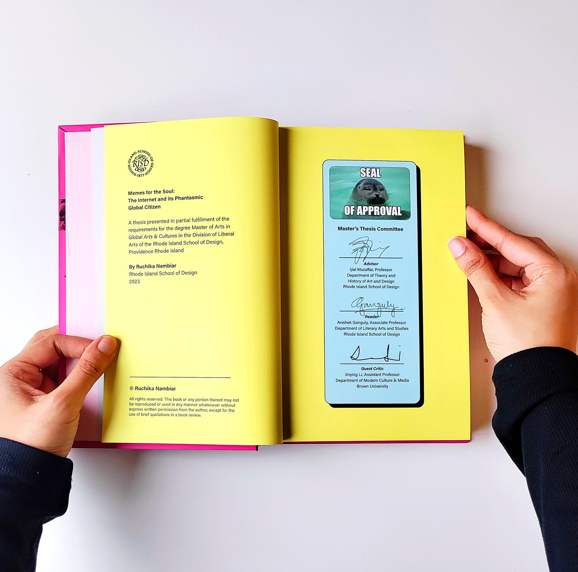 A hardcover book held open by a pair of hands to show two of its pages.