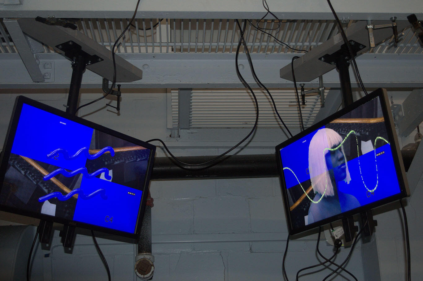 Two ceiling-mounted screens show a deep violet wave symbol (left) and a blue figure with white hair (right). Both have a background resembling a four-panel security monitor.