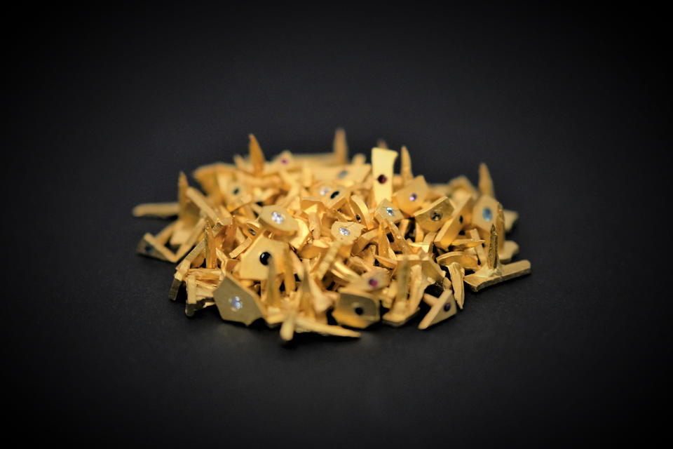 Photograph of a pile of small gold nails with diamonds