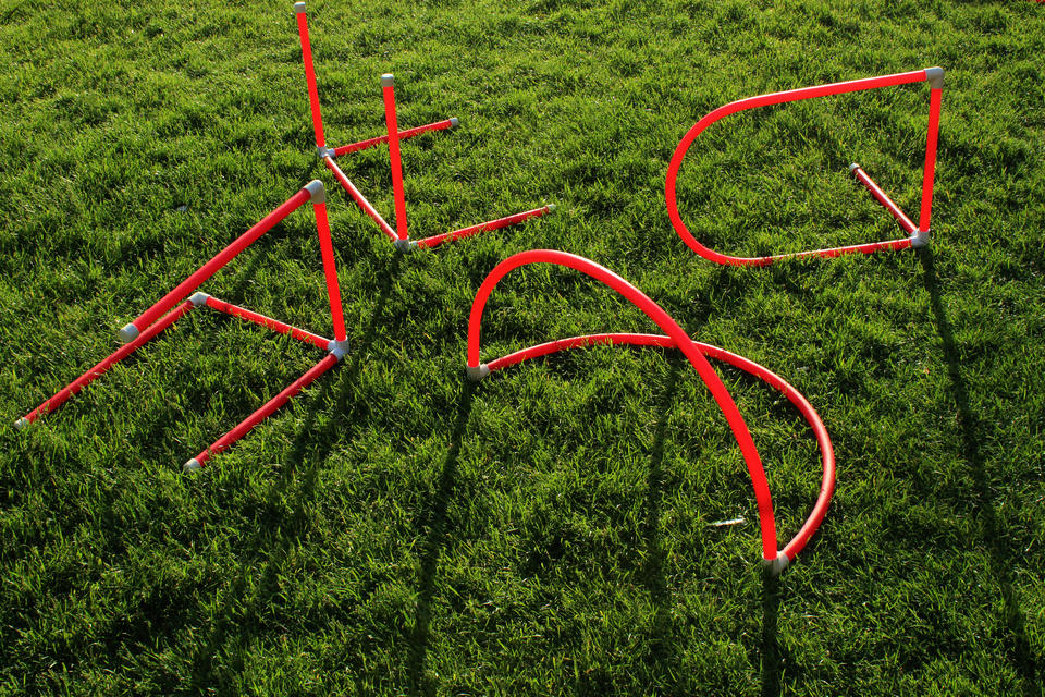 Photo of red PVC letterforms on grass