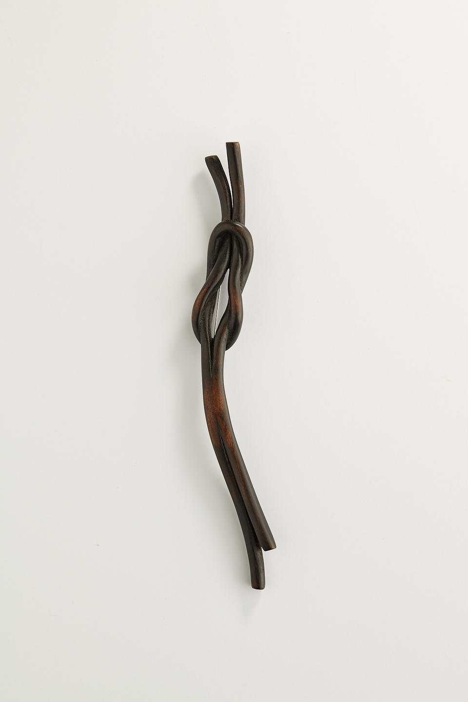 A dark knot brooch carved from wood