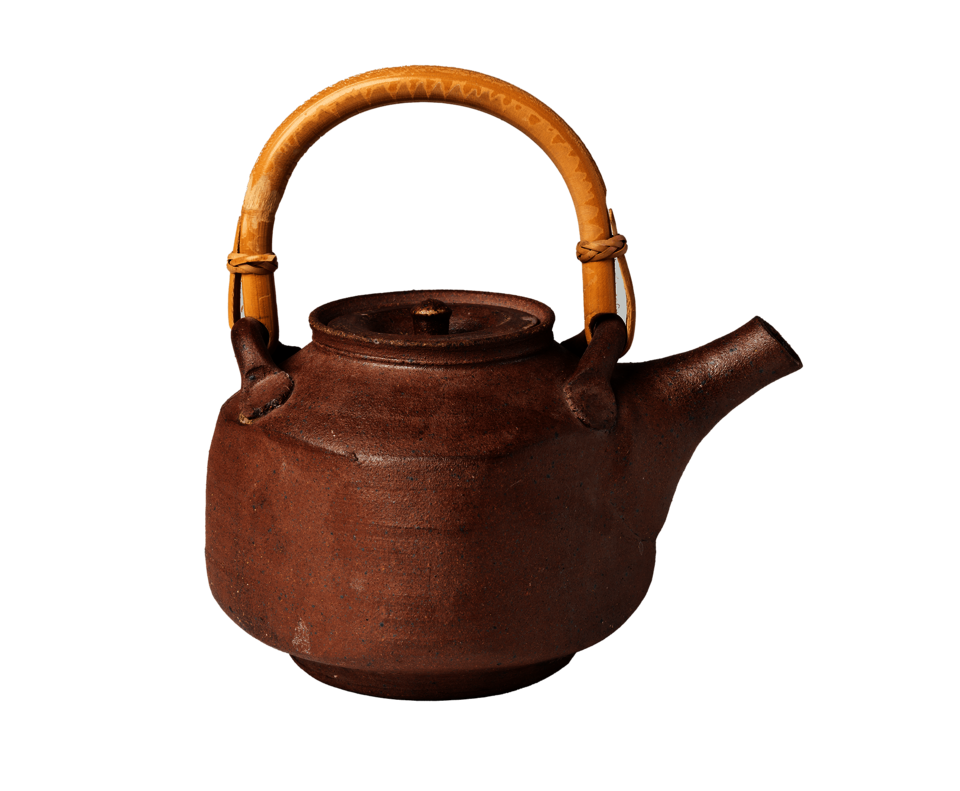 Square-shaped brown teapot resting on circular foot. Rounded tan handle on top of teapot.