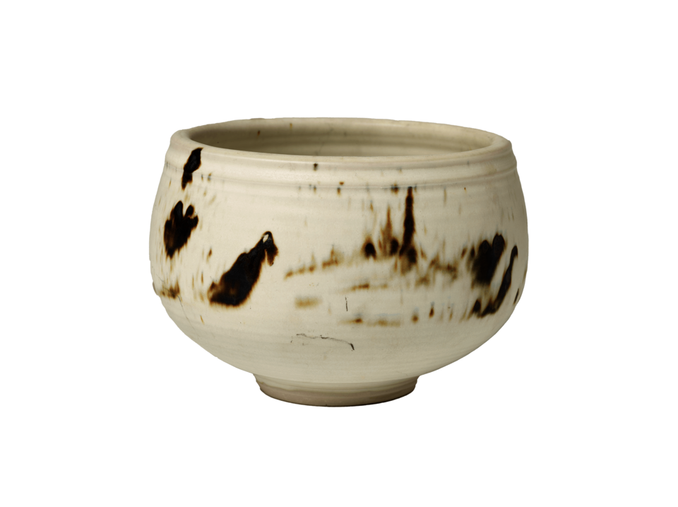 White bowl on a small circular foot with irregular brown marks. 