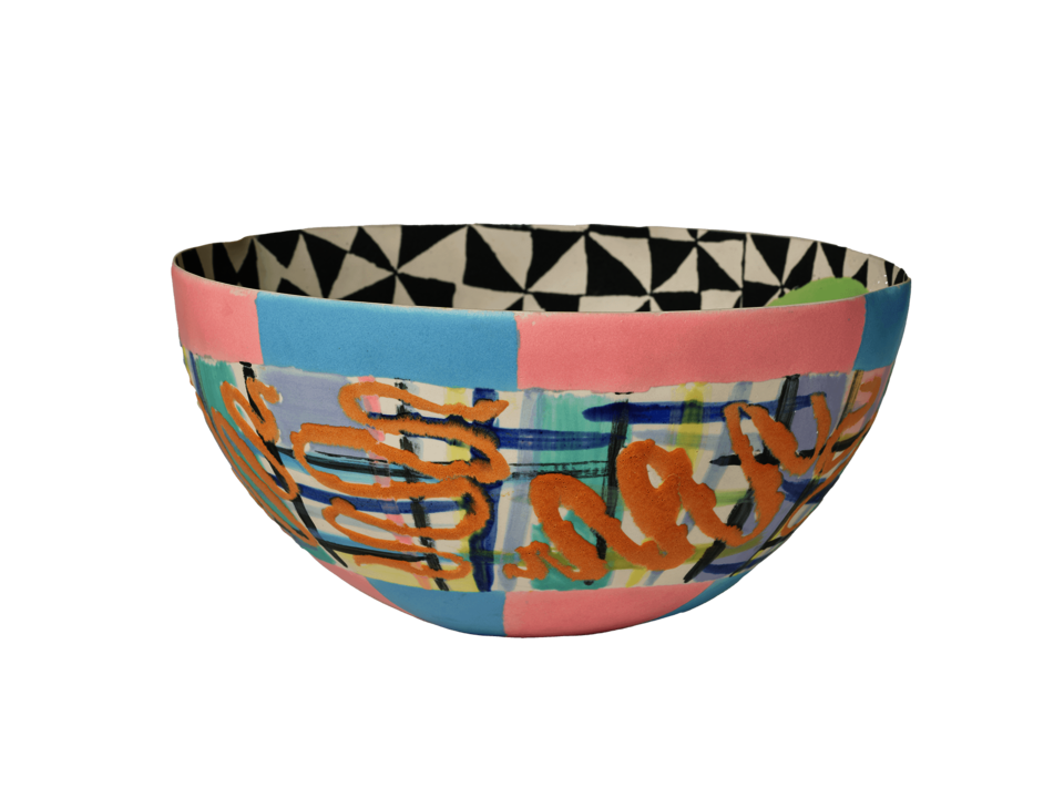 Bowl with multicolored lines and blocks of blue and pink at the top and bottom of exterior. Black and white geometric design on the interior. 
