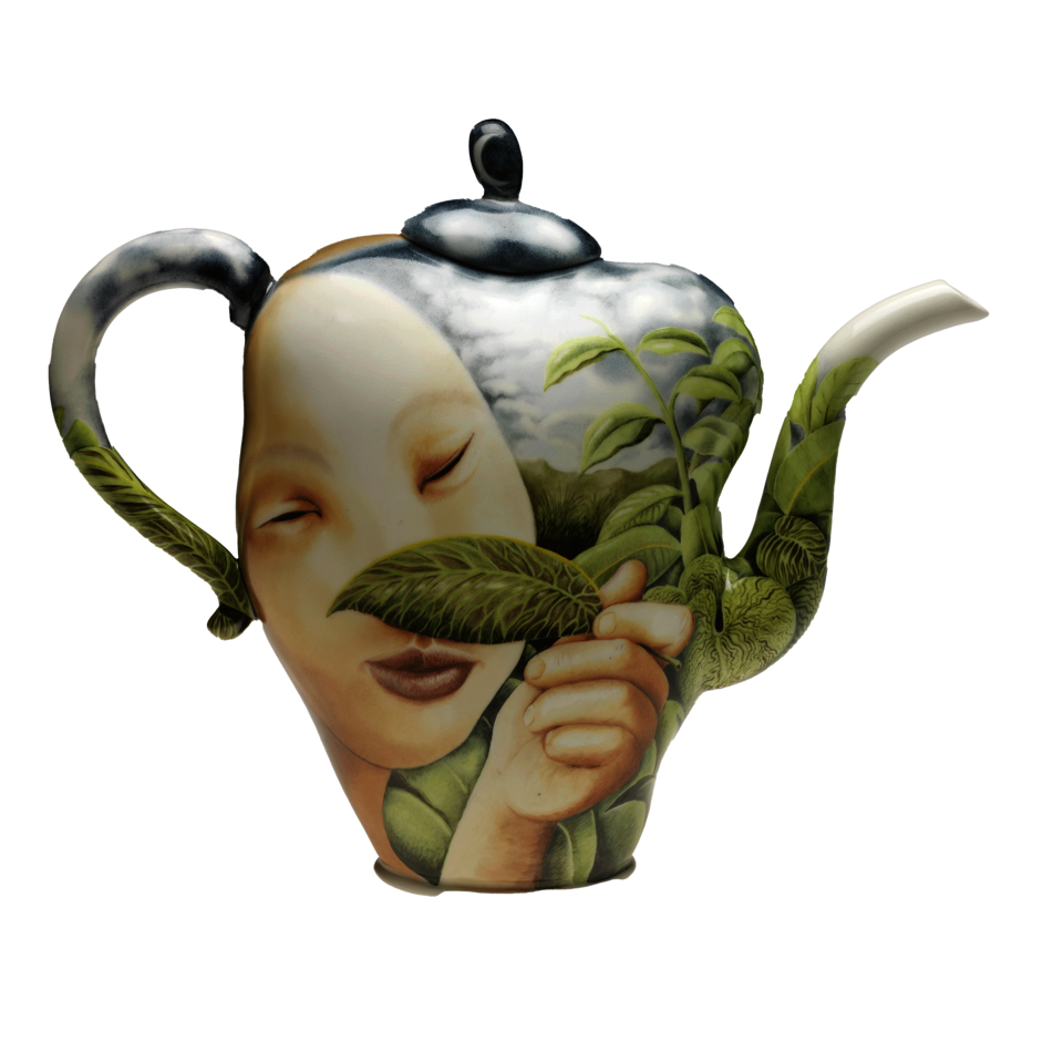 Teapot with spout facing right. It is painted with a large, light-skinned face and hand holding a green leaf partially over face, surrounded by tropical green leaves and cloudy blue sky