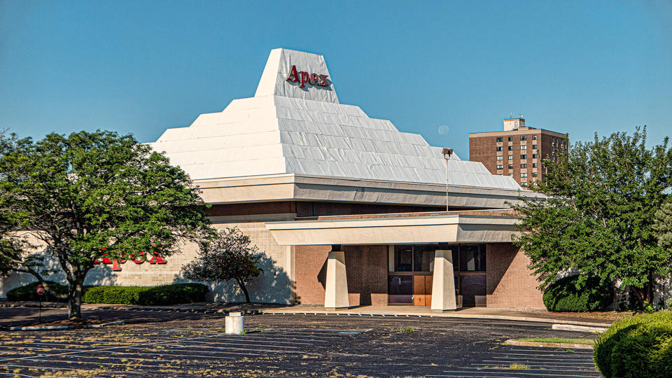 color photograph of the Apex department store in Pawtucket, RI. The 1960s era building has a distinctive white roof shaped like a ziggurat, or stepped pyramid.